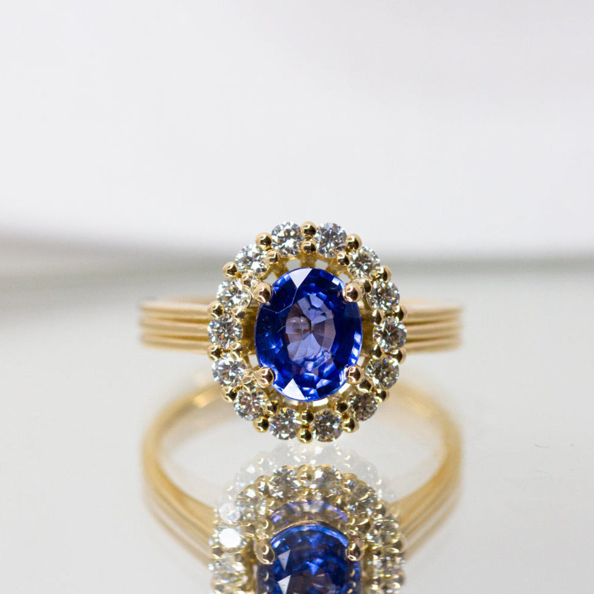 Bague entourage ovale, anneau godron orné d'un saphir bleu et d'un pavage de diamants ronds en or jaune Fairmined 750/1000
Création sur-mesure de joaillerie  éthique et artisanale