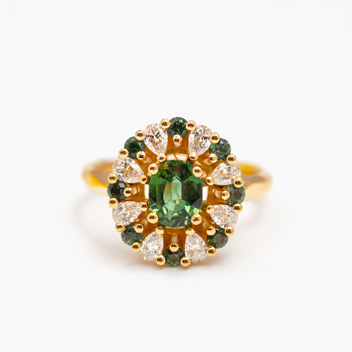 Bague entourage sur-mesure en or jaune 750/1000 fairmined sertie d'un saphir vert ovale et d'un pavage de diamants taille poire et saphirs verts brillant
Conception et fabrication dans notre atelier de joaillerie éthique à Paris