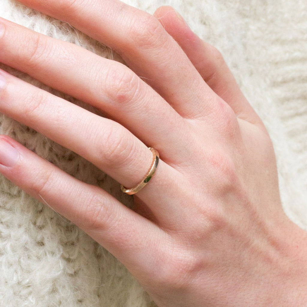 Alliance en or pour femme, réalisée en or rose-champagne. L'anneau est lisse en surface et texturé sur les bords.