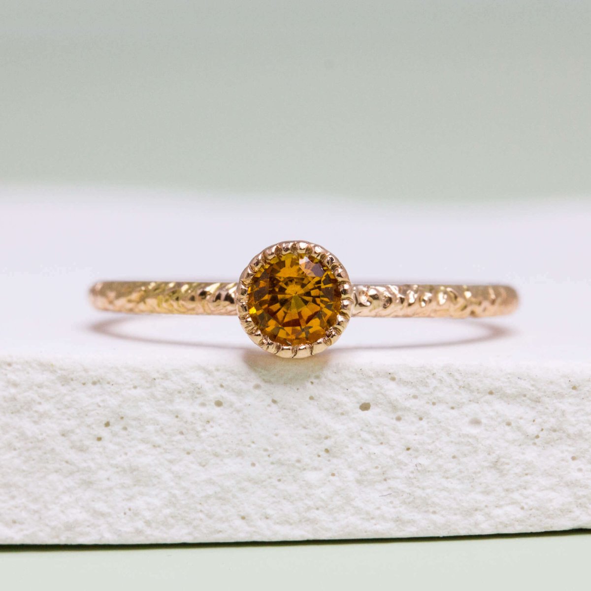 Bijou artisanal en or rouge orné d'un saphir orange de 4 millimètres.