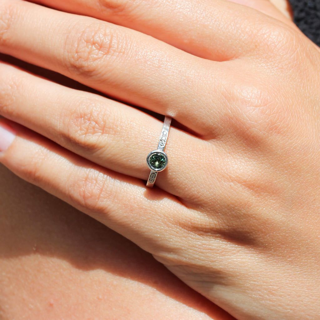 Bague éthique en or blanc ornée de diamants et d'un saphir vert.