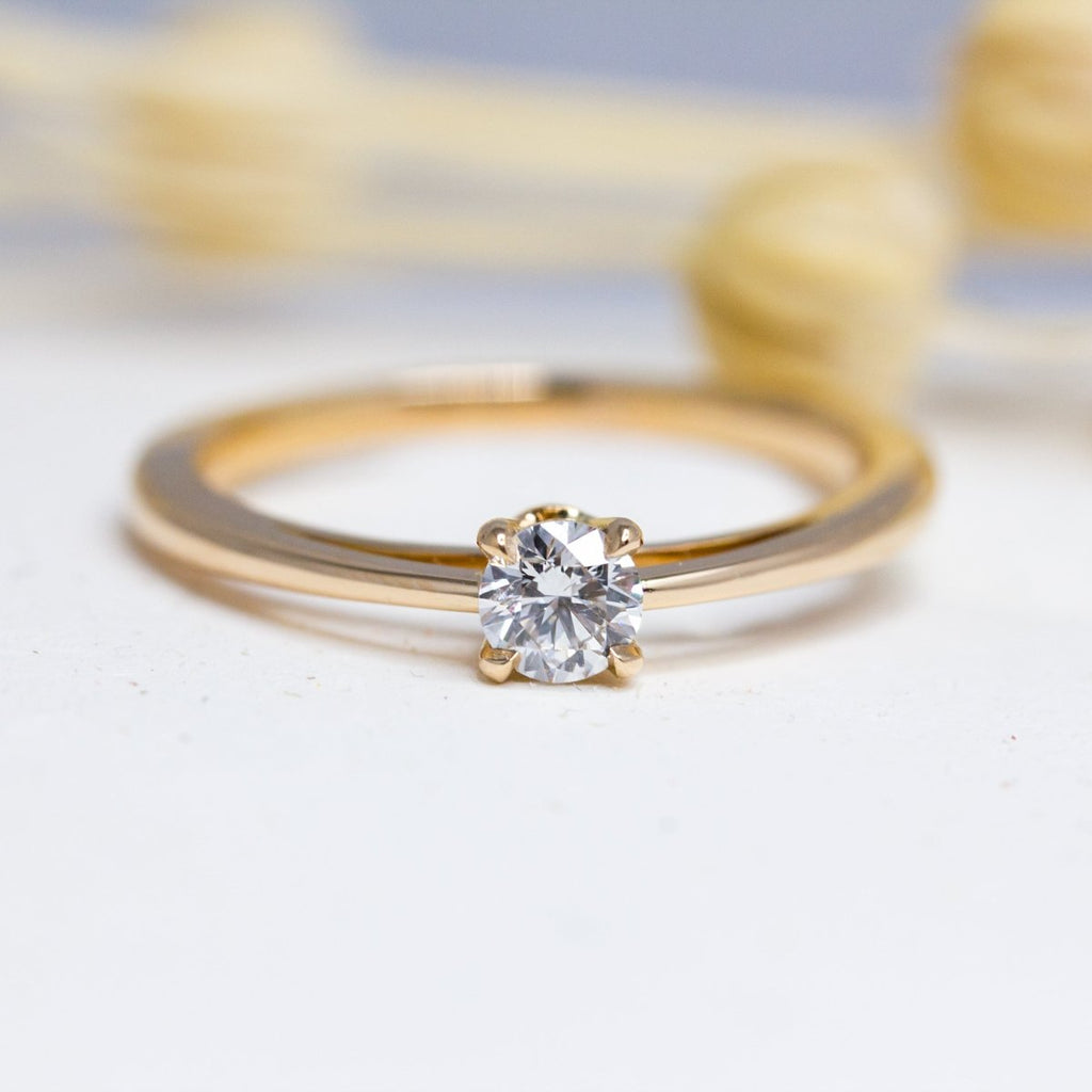 Bague de fiançailles en or rose avec un joli diamant de synthèse aux reflets brillants.