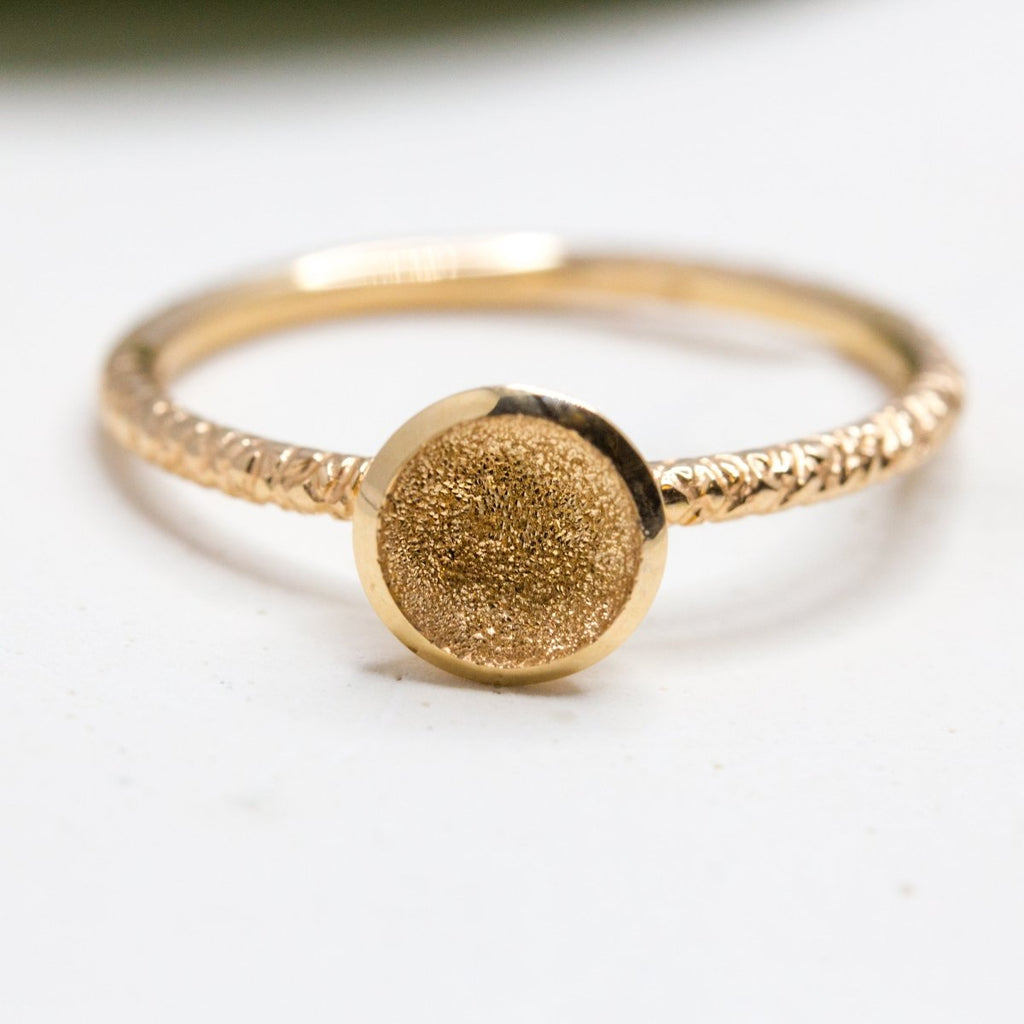 Bague en or Fairmined, ornée d'un anneau texturé et d'un cercle creusé aux reflets scintillants.