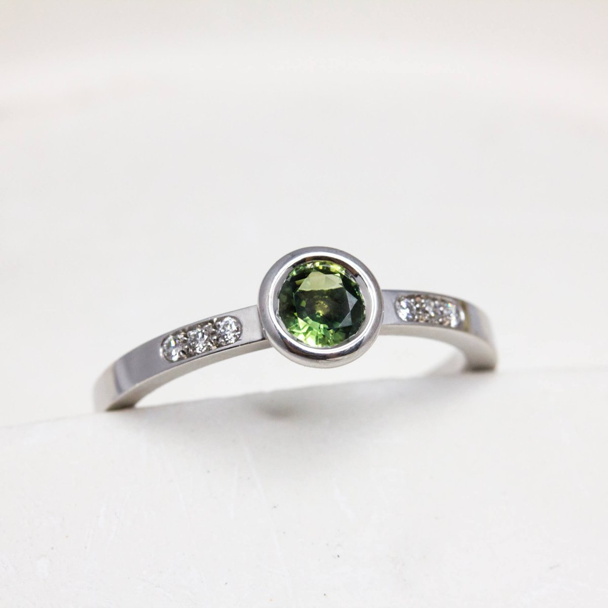 Bague originale en or blanc 18 carats Fairmined ornée de 6 diamants et d'un saphir vert.