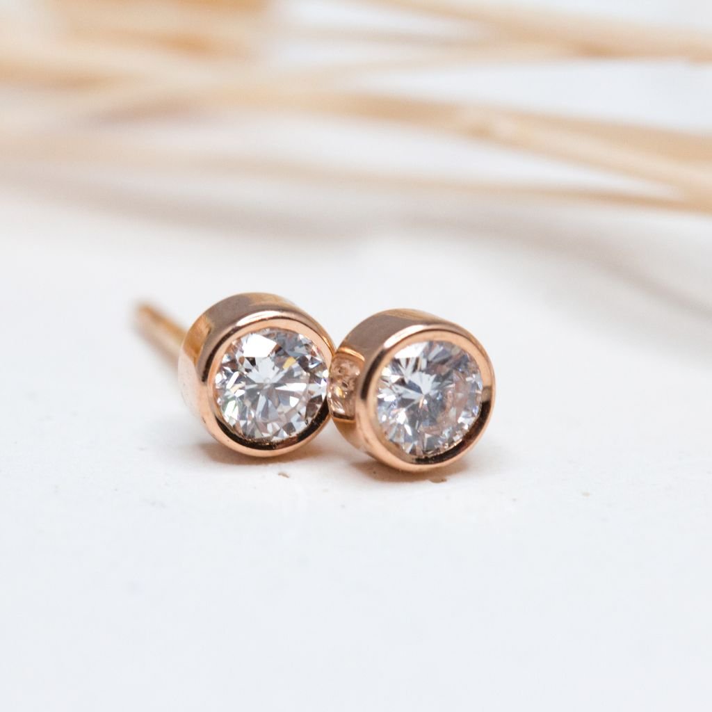 Boucles d'oreille Solférine réalisées en or rouge 18 carats Fairmined. Leur serti clos enserrent deux diamants de synthèse.