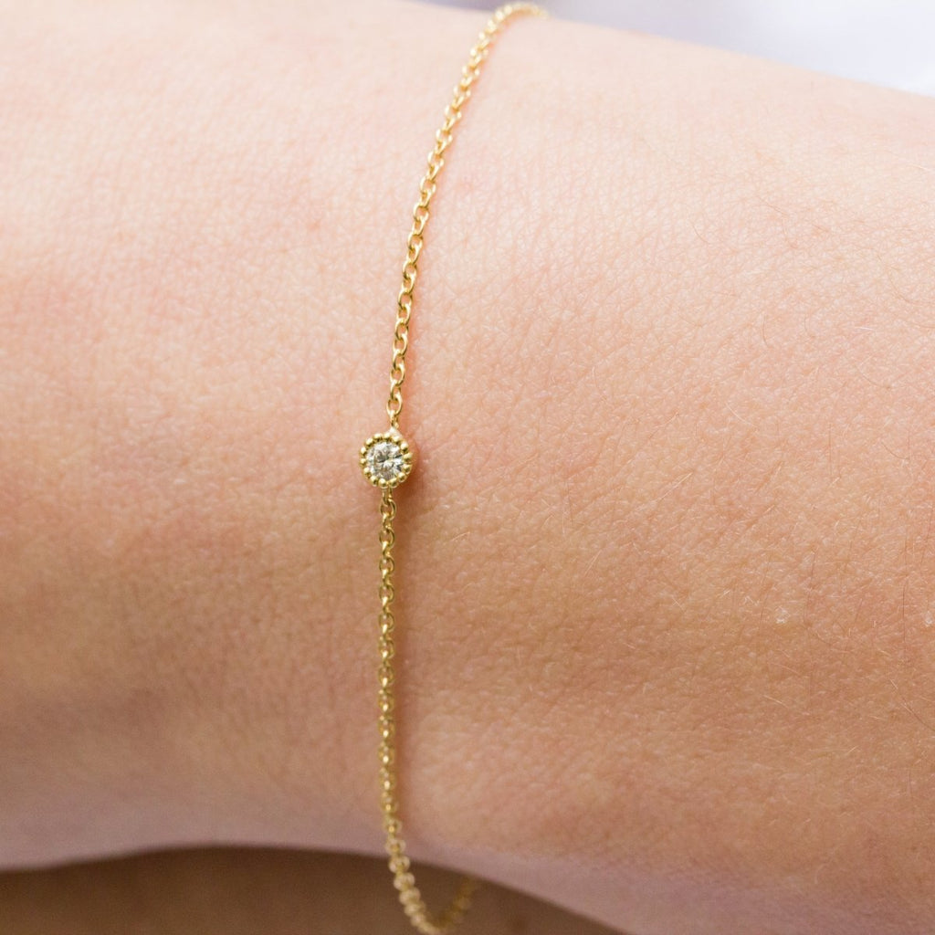 Bracelet épuré avec une chaîne en or jaune et un petit diamant au centre.