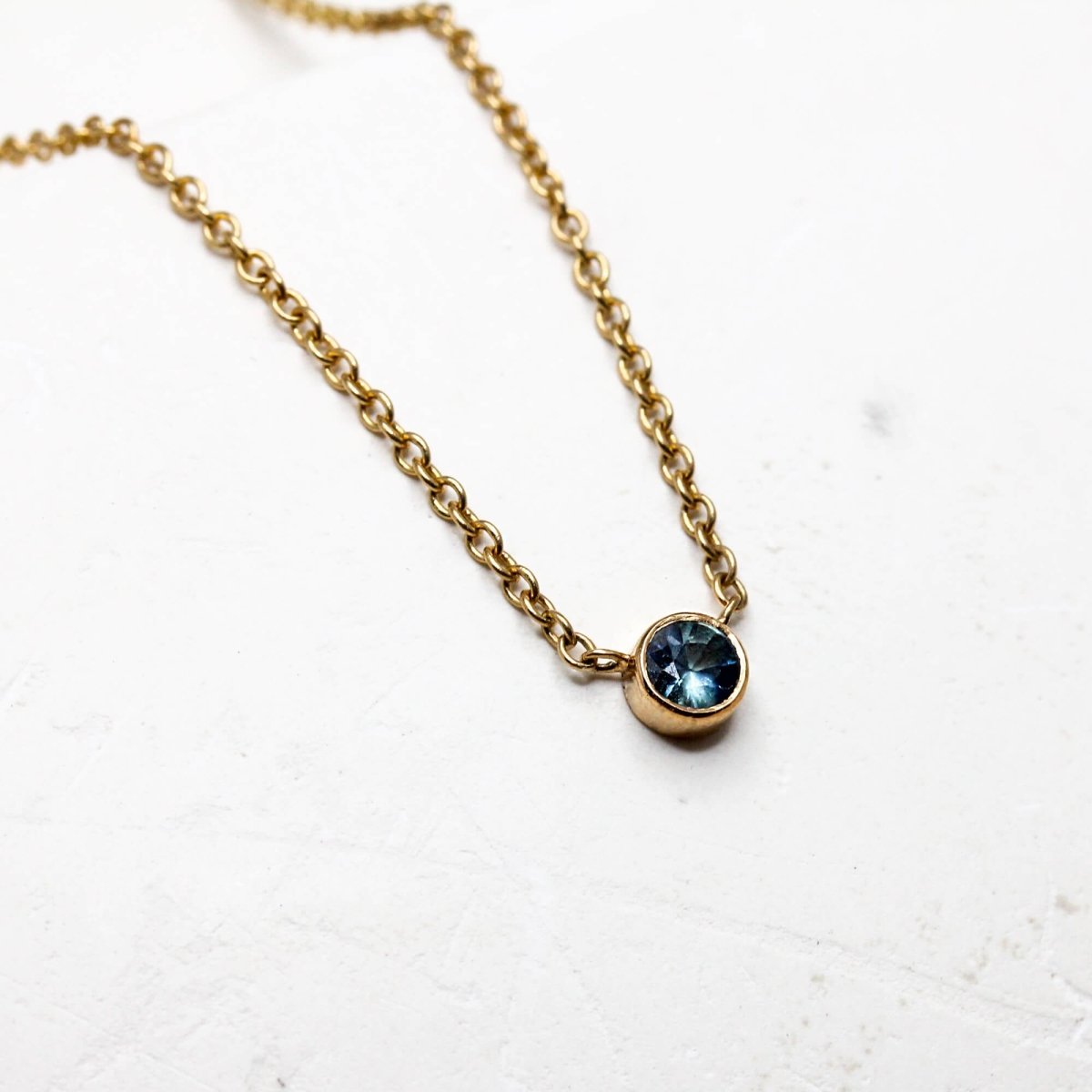 Collier en or éthique orné d'un saphir bleu.